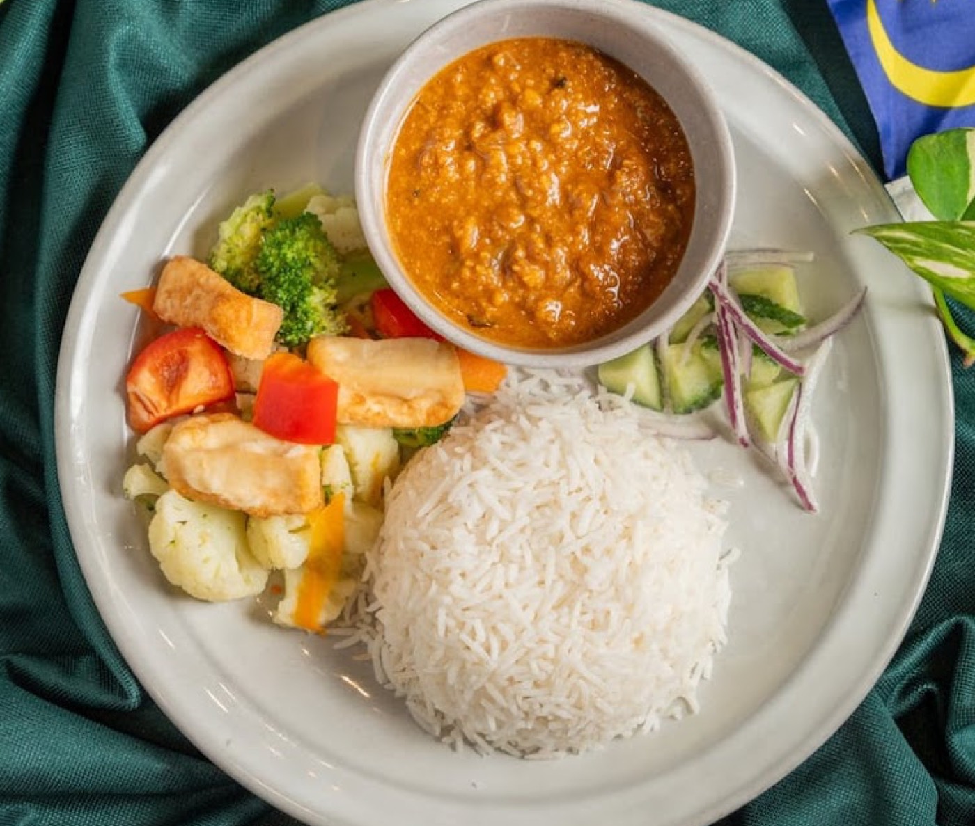 Curry served with basmati rice, tofu and vegetables on a white plate