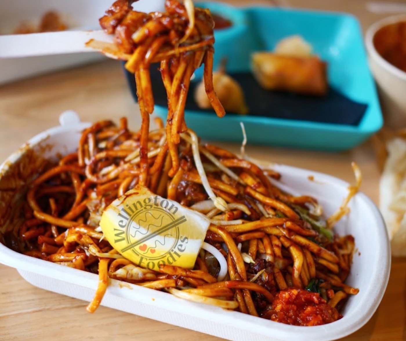 Mee goreng noodles with bean sprouts and lemon in a takeaway box