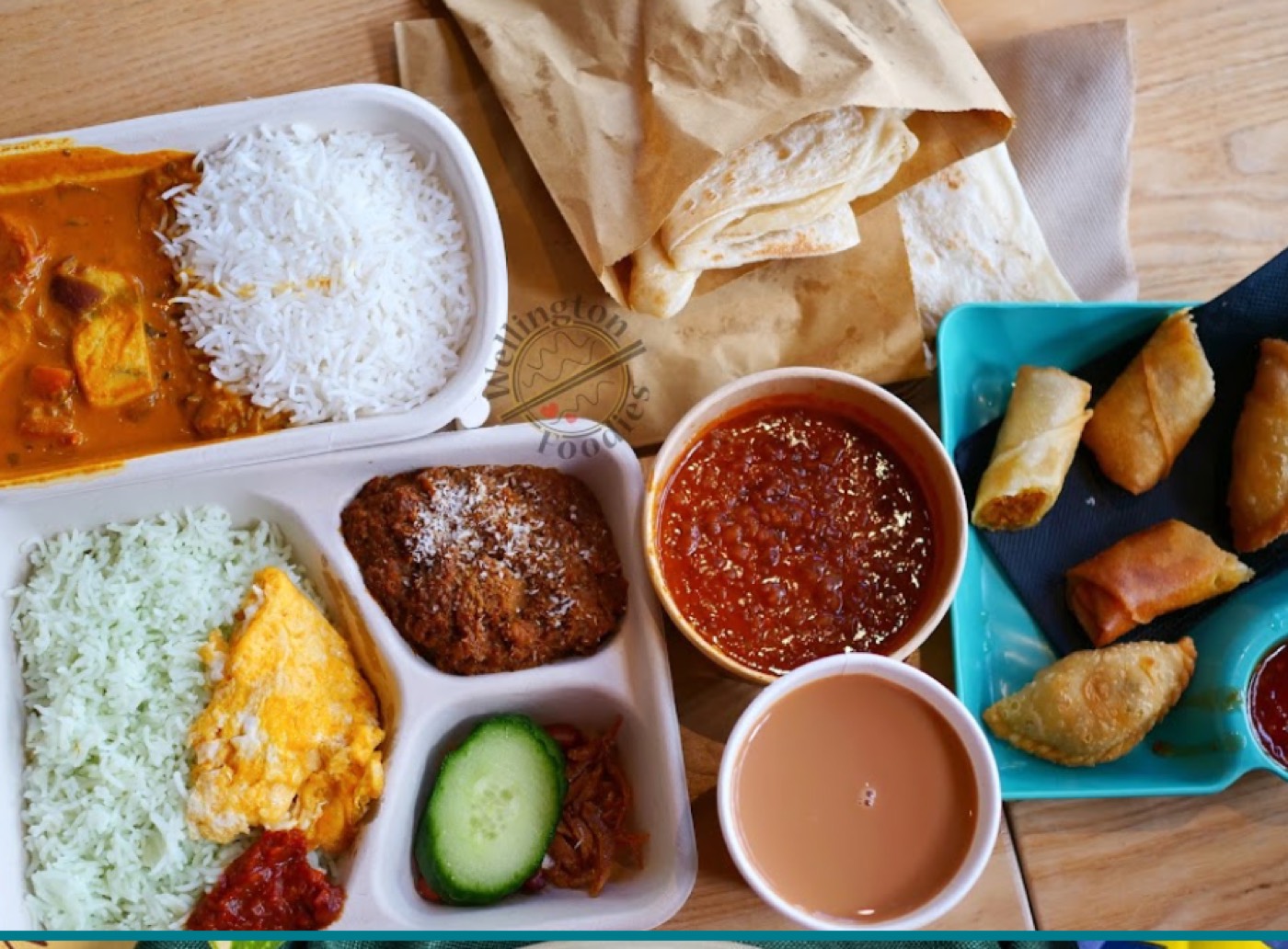 Spread of curry, rice, roti canai, sambal, spring rolls, curry puffs and teh tarik