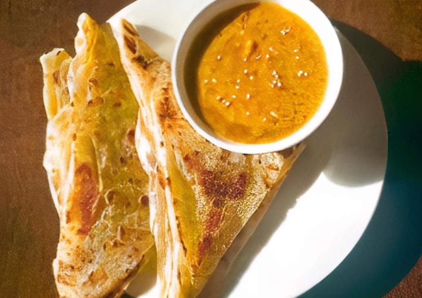 Roti canai served with a bowl of curry sauce