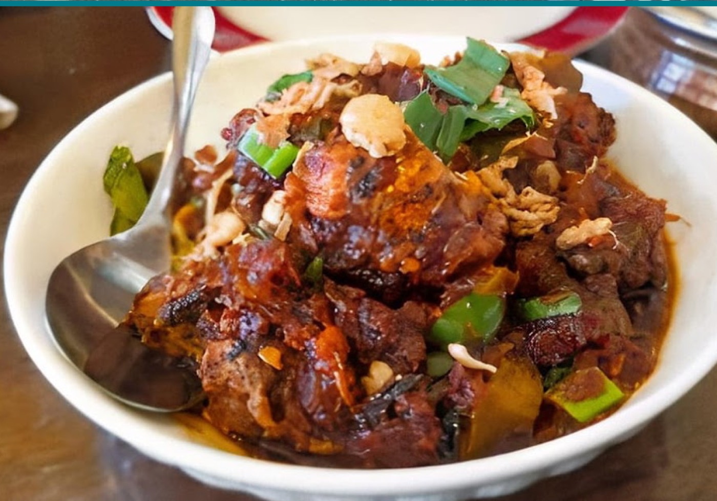 Bowl of slow-cooked rendang with capsicum and greens